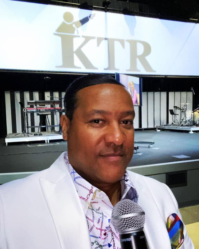 Kevin T. Robertson in white jacket with KTR screen behind him